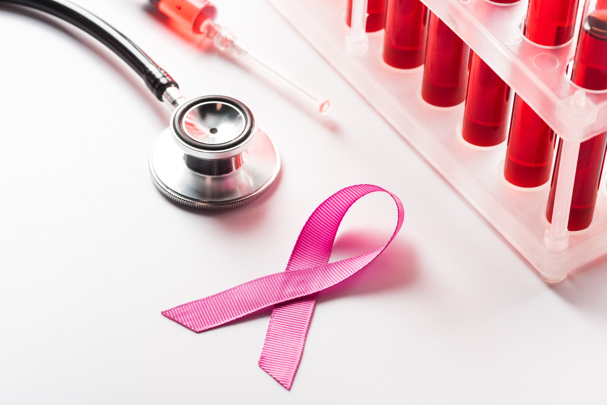 close up of Breast Cancer Awareness Ribbon, stethoscope and flasks with blood