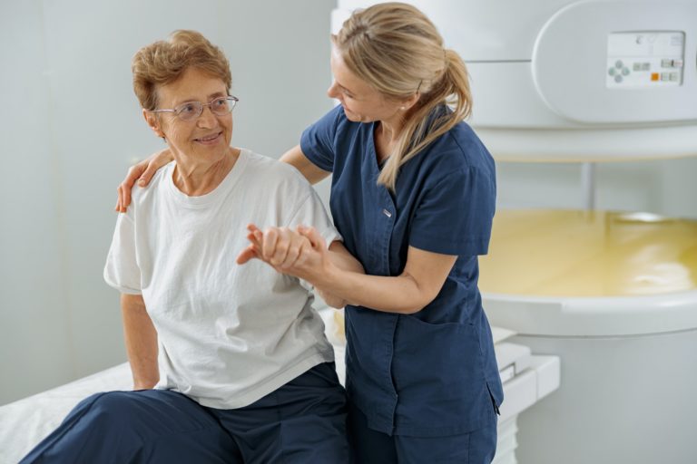 Doctor radiologist help to patient sit after procedure of MRI or CT or PET Scan in clinic